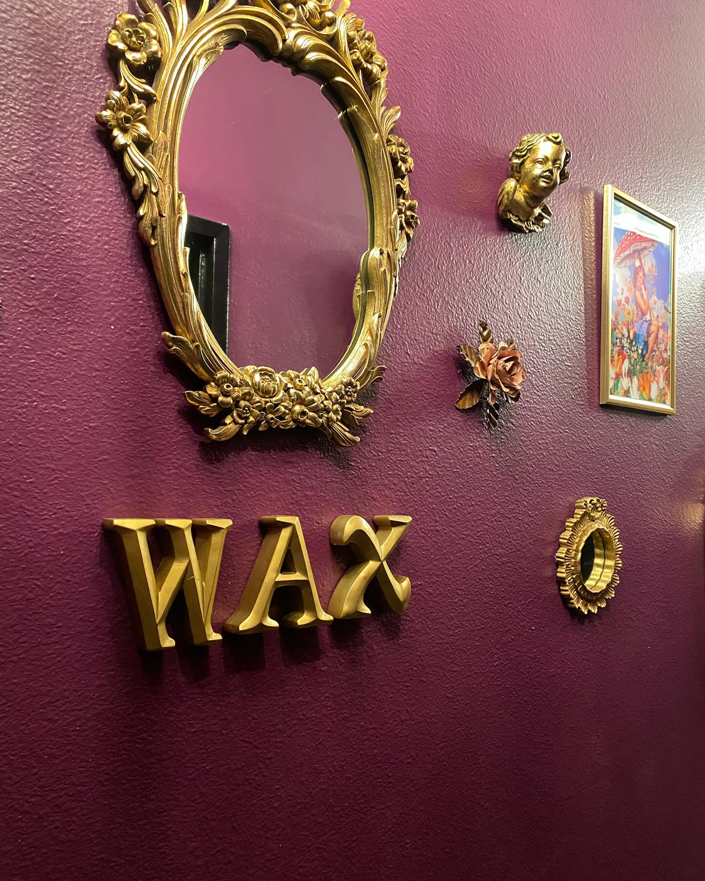 Gold WAX letters and ornate mirror on plum wall